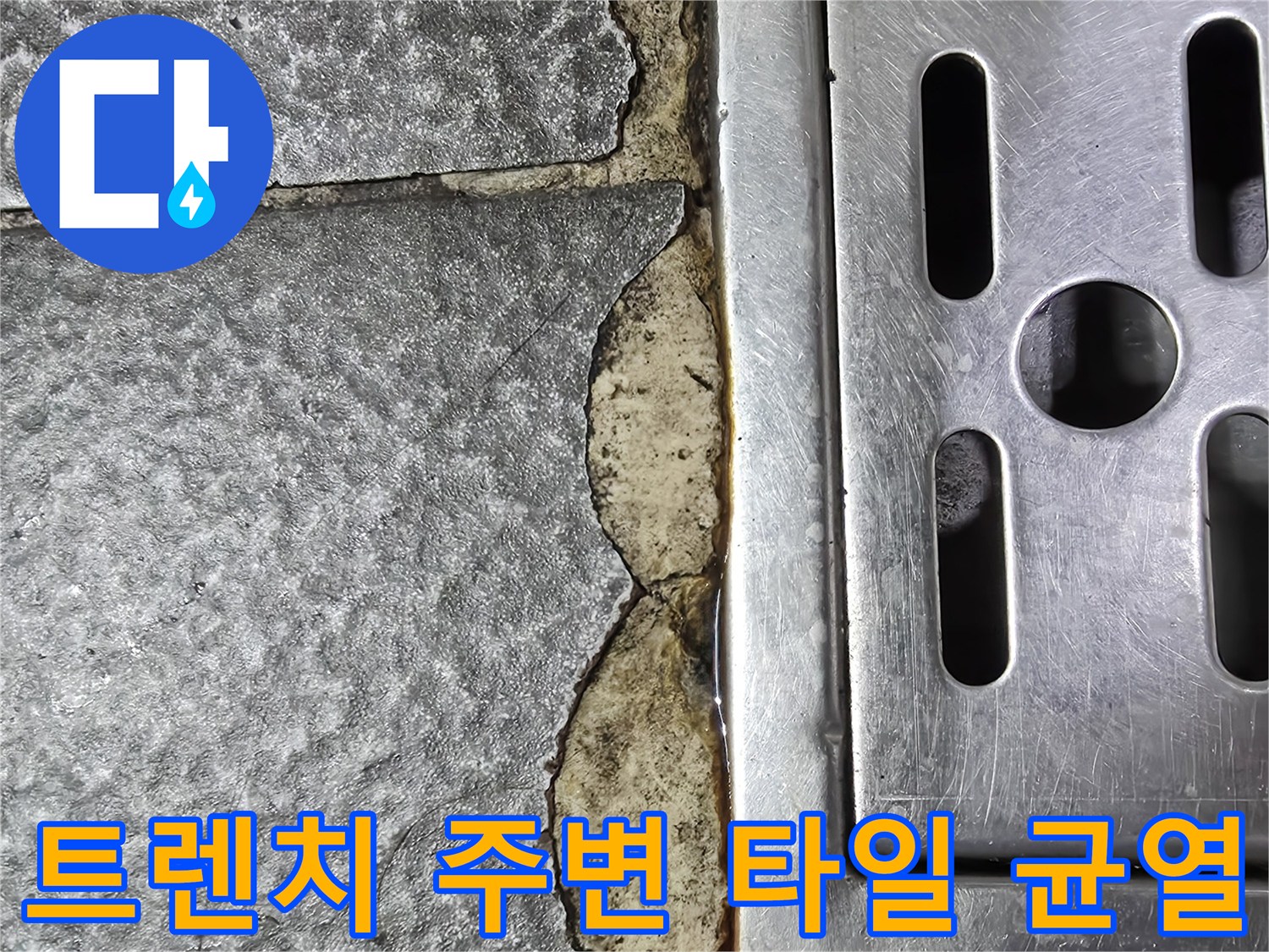 스테인리스 배수 트렌치 인근의 깨진 타일과 틈새를 보여줍니다.