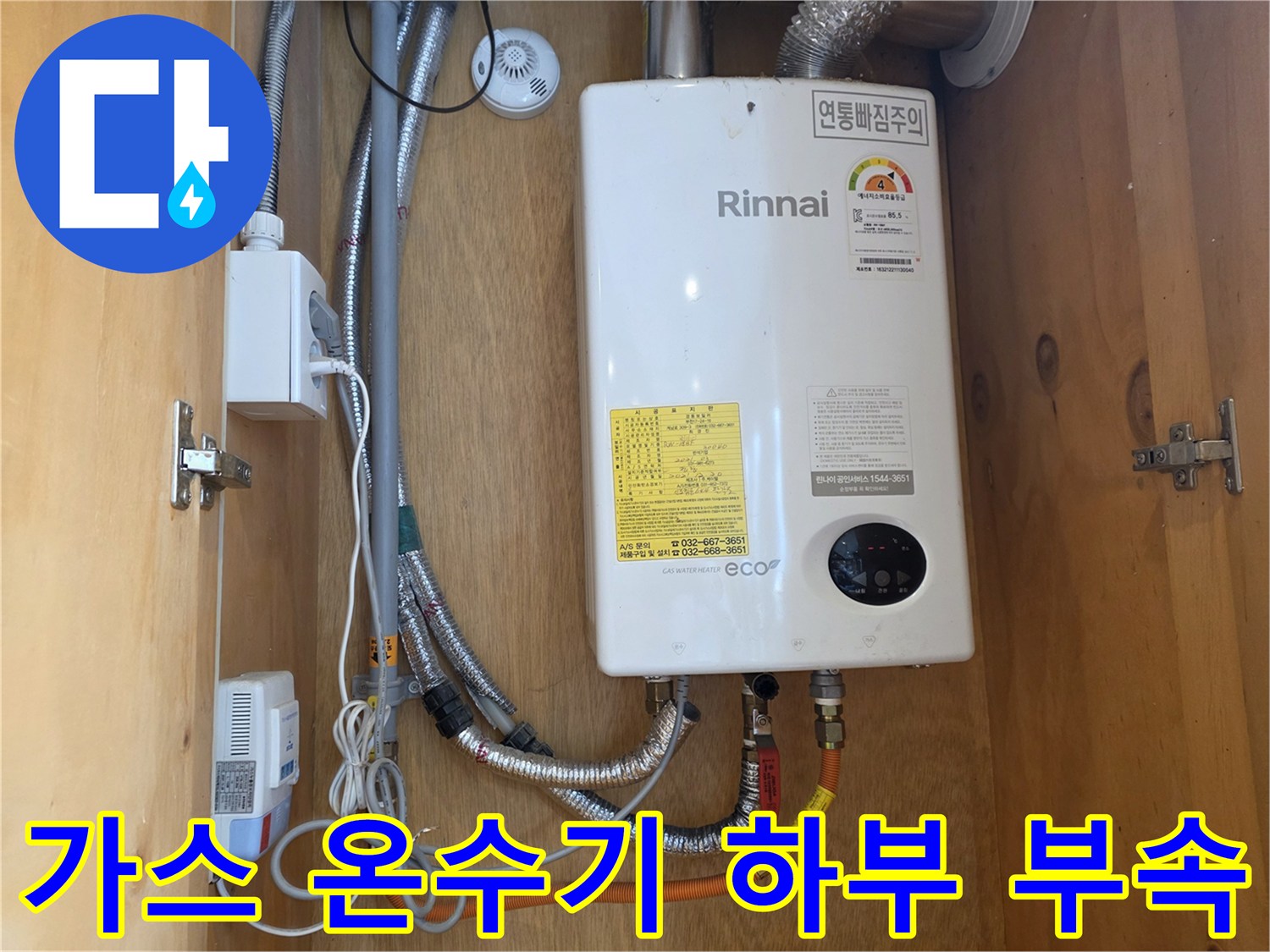 온수기 아래쪽의 금속 호스와 연결된 다양한 배관 부품들