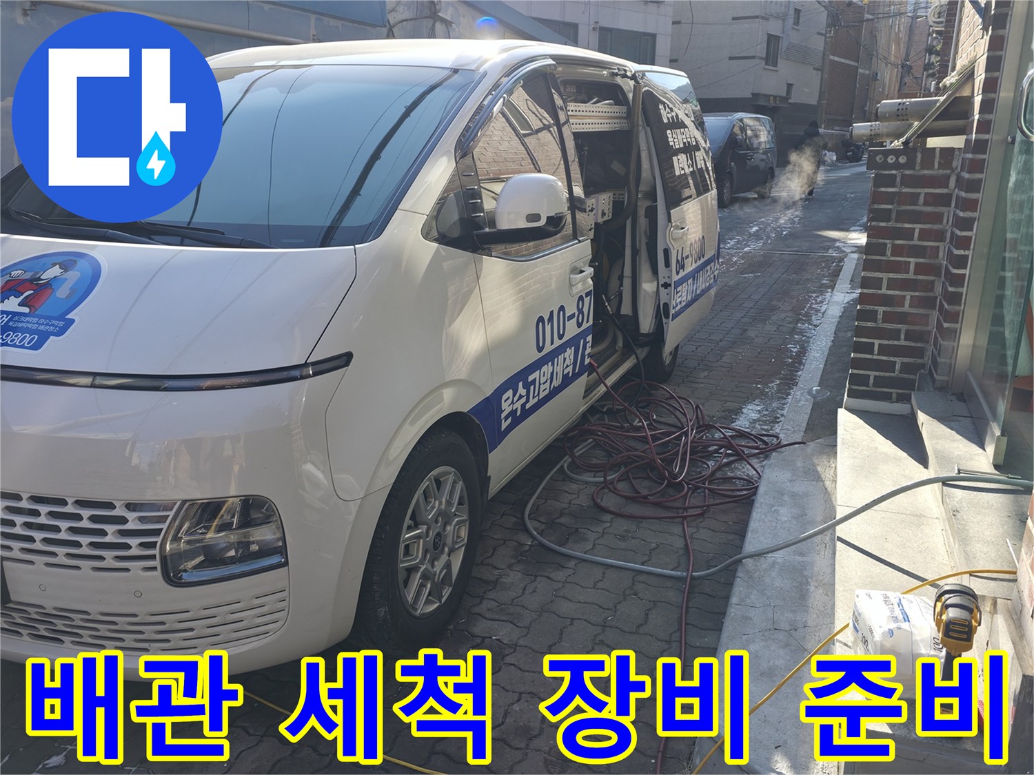 현장 입구에 주차된 작업 차량과 바닥에 놓인 전선 릴