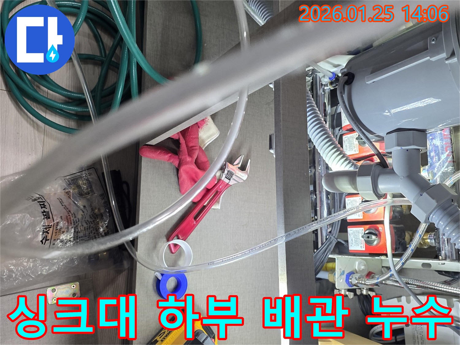 이 사진은-싱크대 하부의-복잡한 배관에서-발생한 누수를-정확하게 탐지하고-수리하기 위해-전문가가-공구를 사용하는-작업 현장을-보여줍니다.