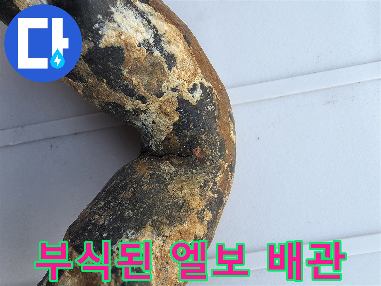 심하게 부식되어 균열이 발생한 금속 배관의 굴절 부위 모습입니다.
