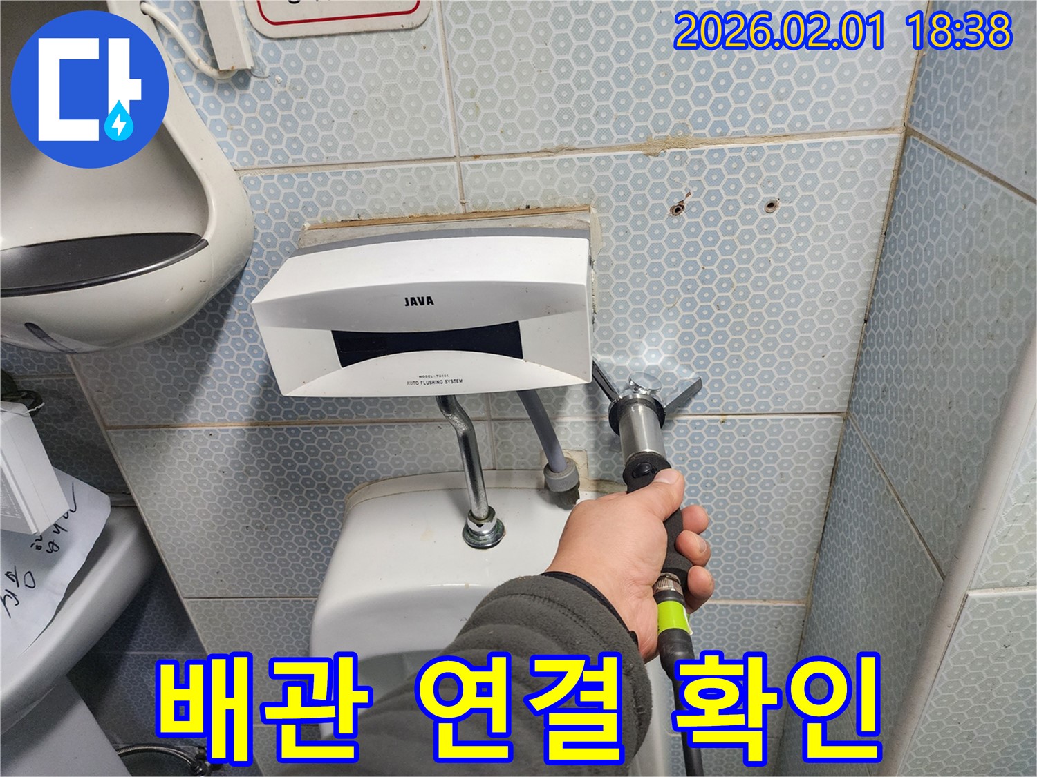 소변기 배관 연결 상태를 확인하는 모습 - 연결이 헐거워지면 누수가 발생할 수 있습니다.