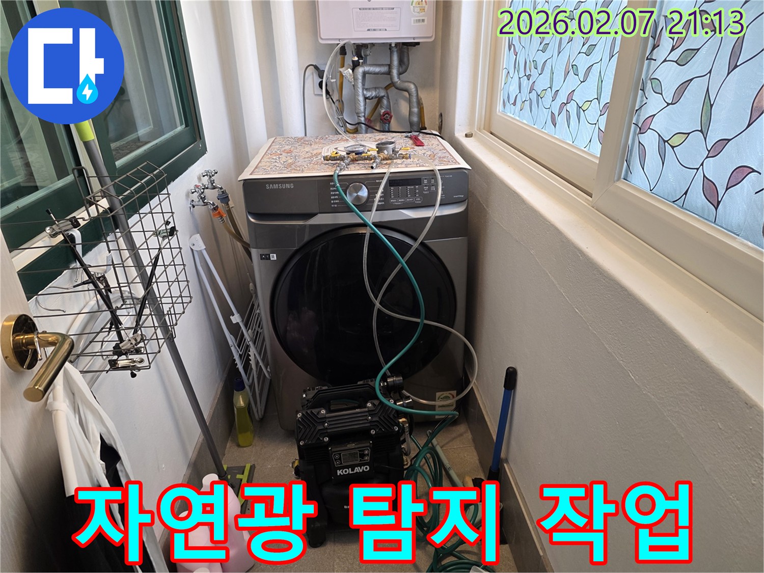 세탁실 창문으로 들어오는 자연광 아래에서-누수 탐지 장비를 활용하여-정밀하게 작업을 진행하는 모습입니다