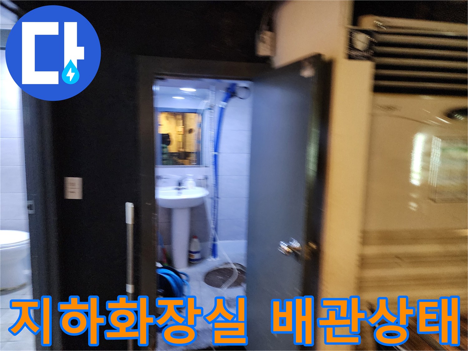 중구 지하 화장실 내부의 노출된 파란색 주름관과 세면대 아래 배관 모습