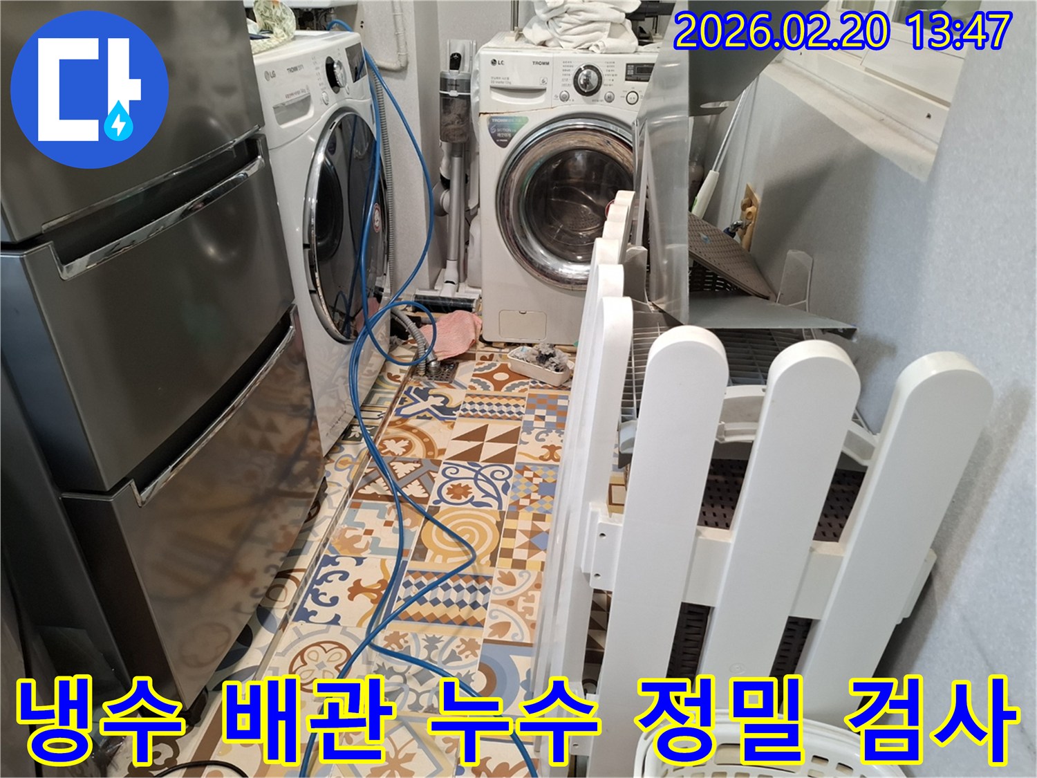 다용도실 바닥에 누수 탐지 장비 호스가 연결되어 있고-냉수 배관 누수 여부를 정밀하게 검사하는 현장입니다.