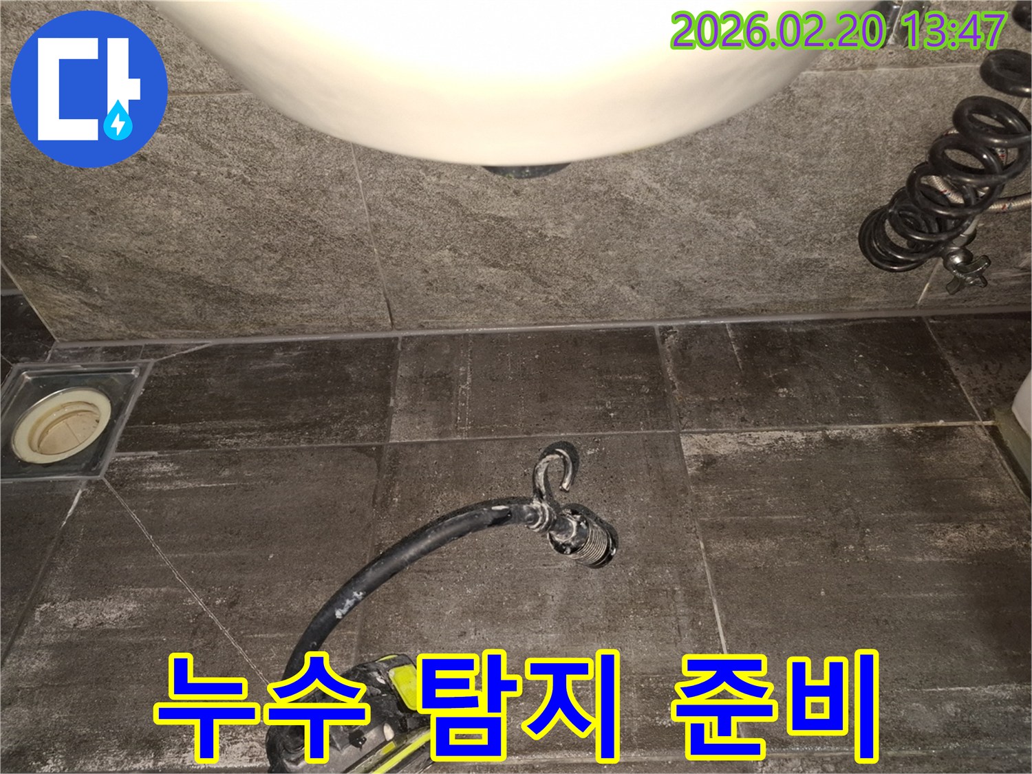 타일 바닥 위에서-누수 탐지 장비가-작동 준비를 마치고-누수 지점 탐색을 시작하려는 모습입니다.