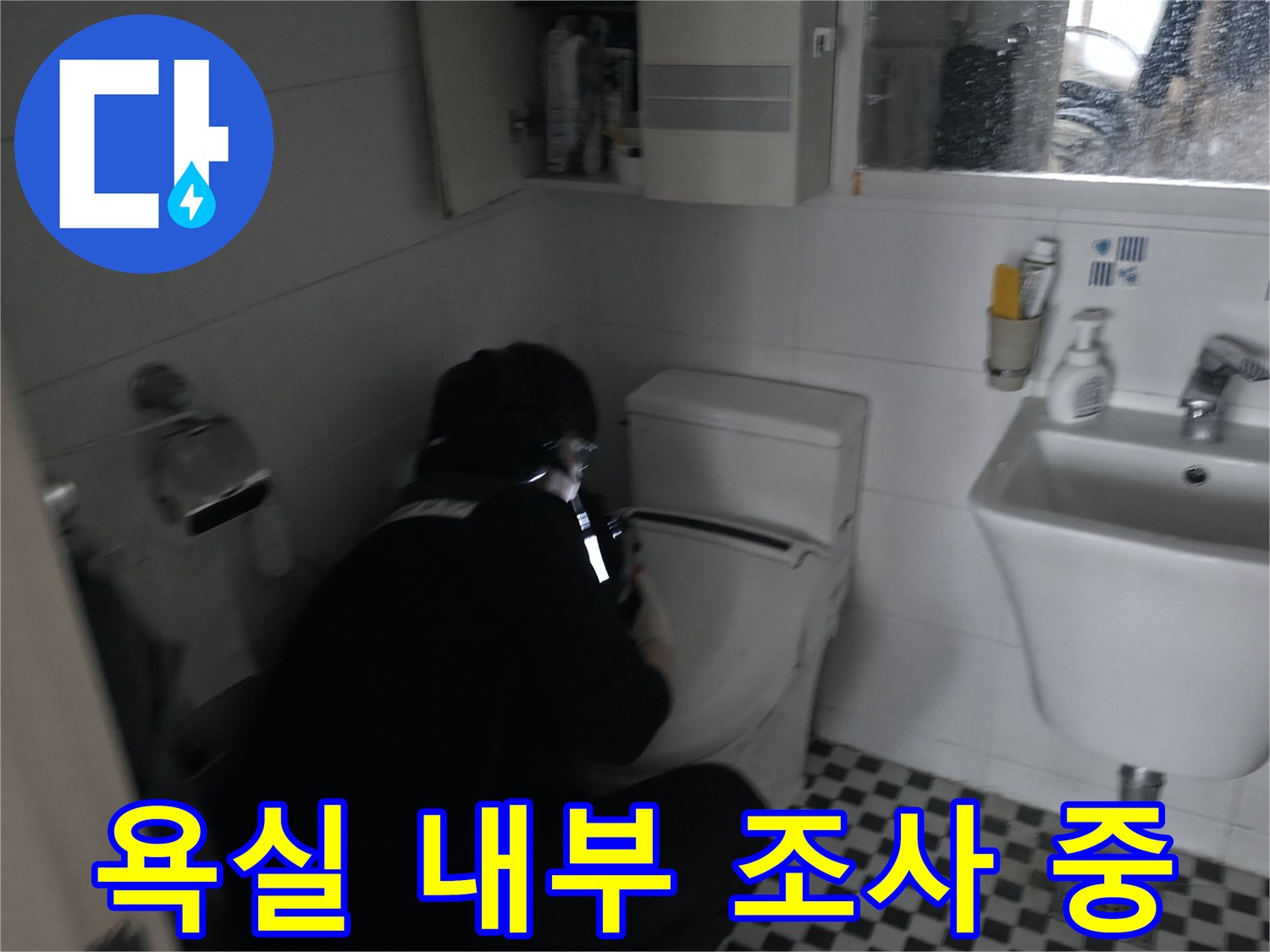 세면대와 변기가 설치된 욕실 공간에서 배관 문제를 확인하는 모습입니다.