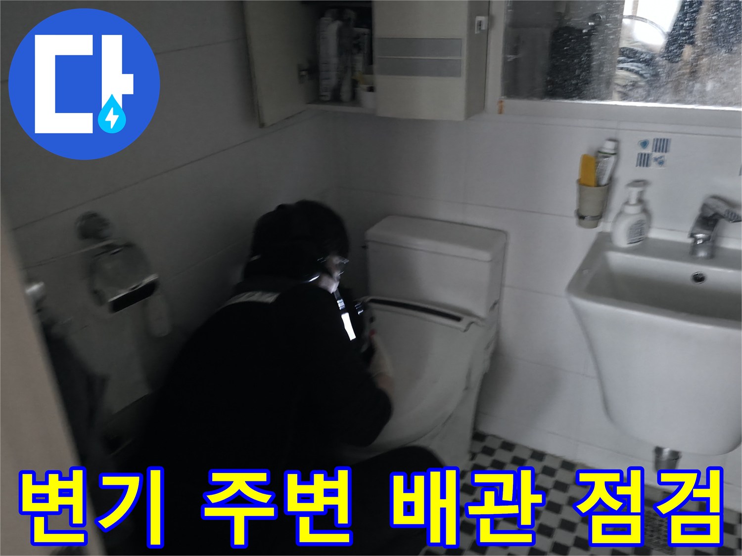 화장실 변기 뒤쪽 배관 부위를 면밀히 조사하고 있습니다.