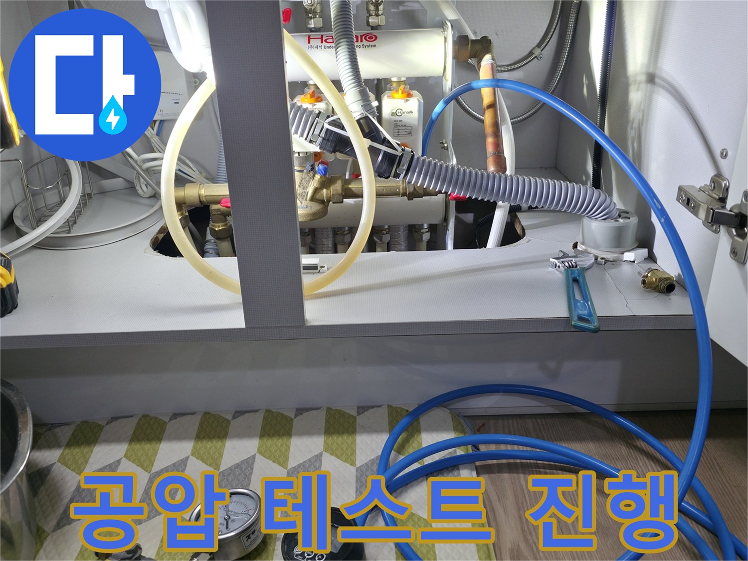 분배기 밸브와 연결된 파란색 호스 및 디지털 압력계 측정 장면