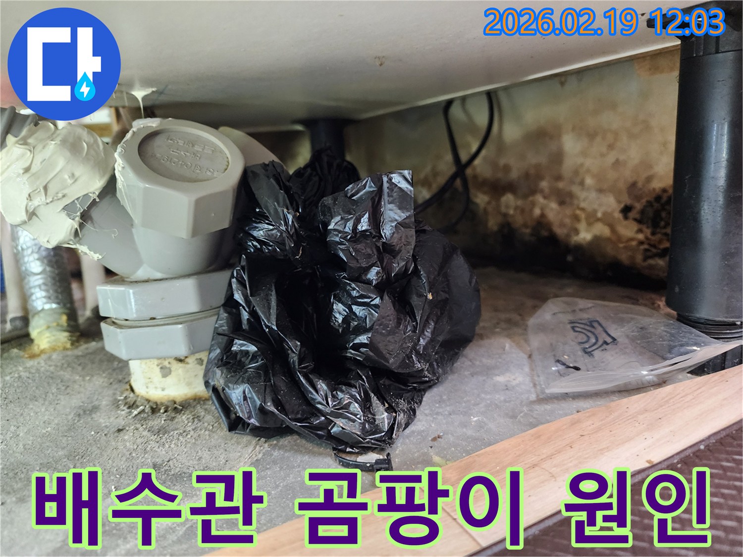 이 이미지는 배수관 주변에 발생한 곰팡이와-오래된 배관 부속-그리고 물샘 흔적을 보여줍니다.