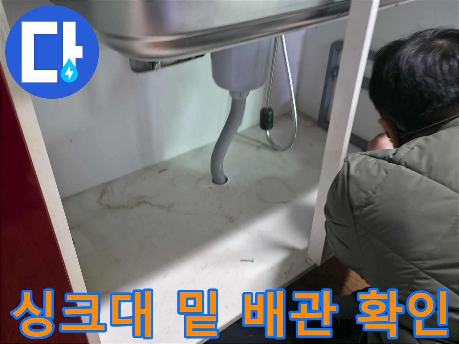 싱크대 하단 은색 호스와 연결 부위의 누수 여부를 조사하는 장면