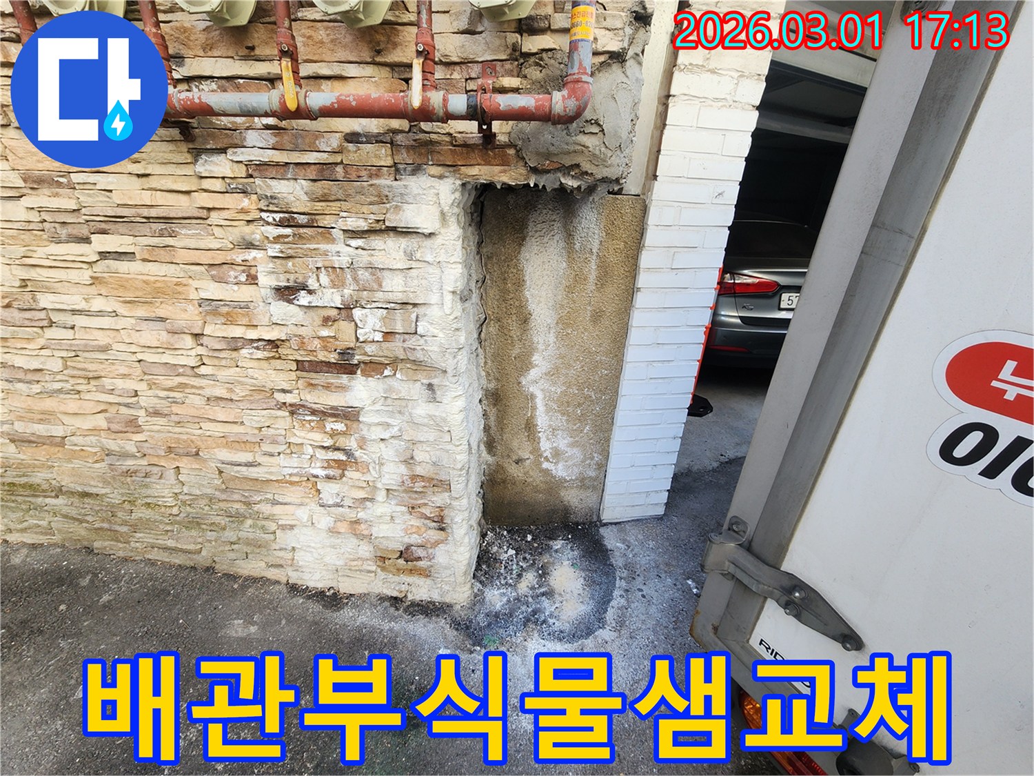 건물 외벽에 설치된-부식된 배관에서-물이 새어 나와-벽면이 젖고-바닥에 물이 고인-누수 현장