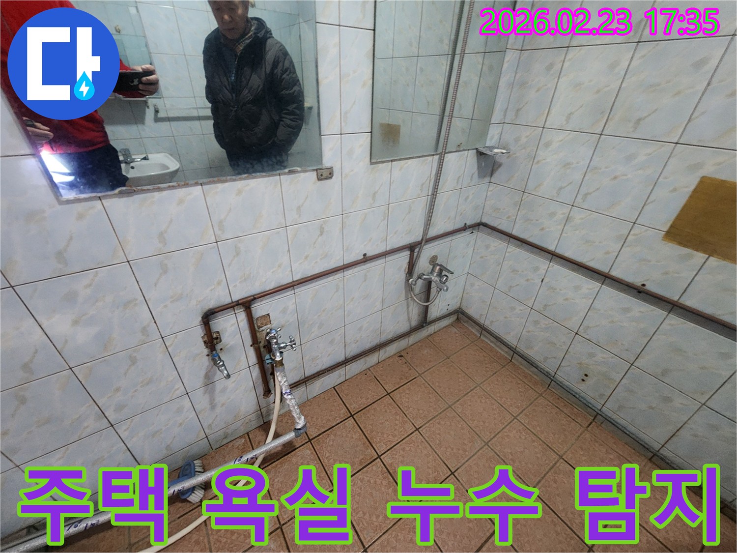 주택 욕실의-노출된 수도 배관에-누수 탐지 장비를-연결하여-정밀 검사를 진행하는 모습