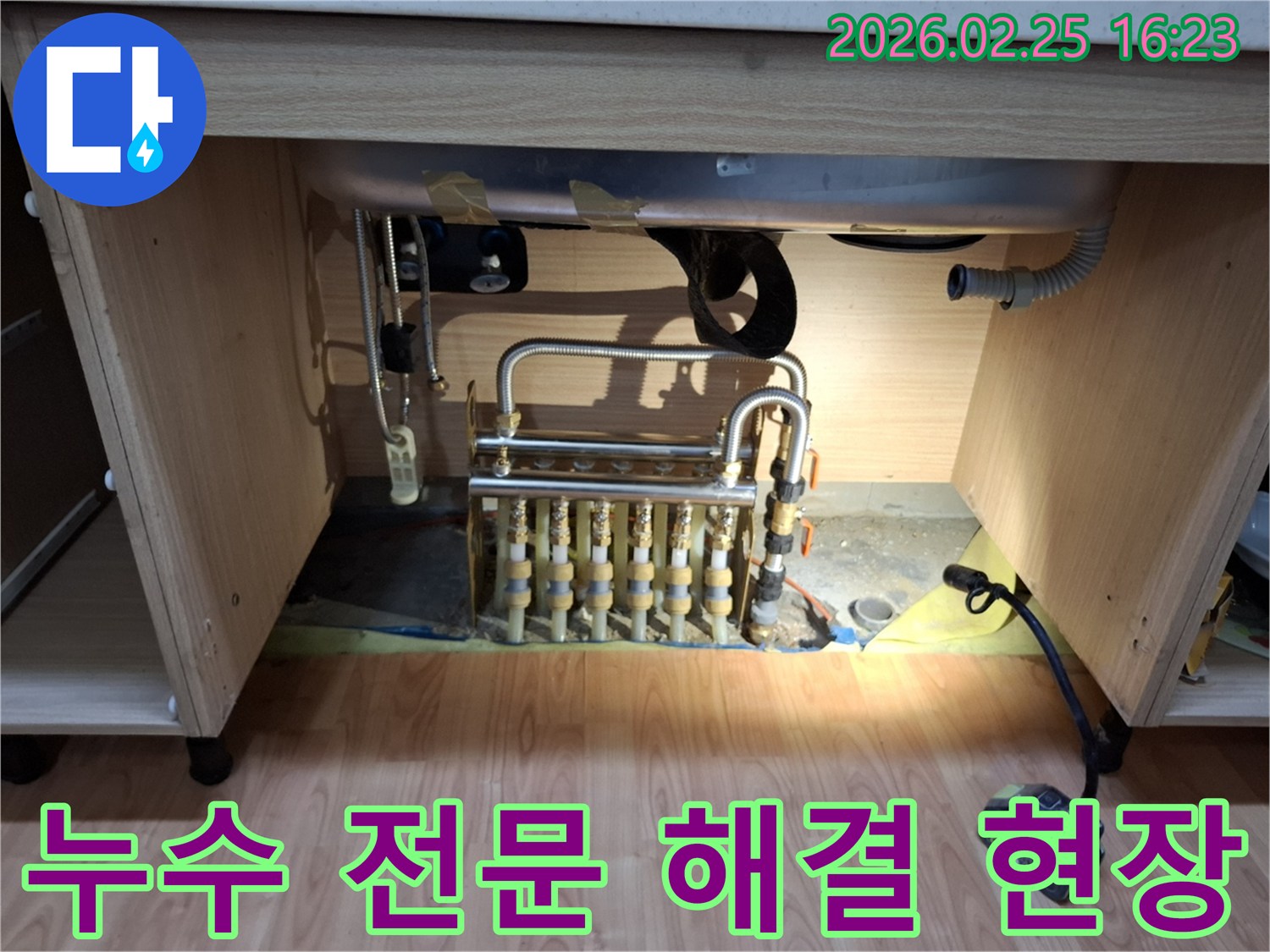싱크대 하부의 배관 분배기에서 발생한 누수를 전문적으로 해결하기 위해 점검하는 모습입니다.