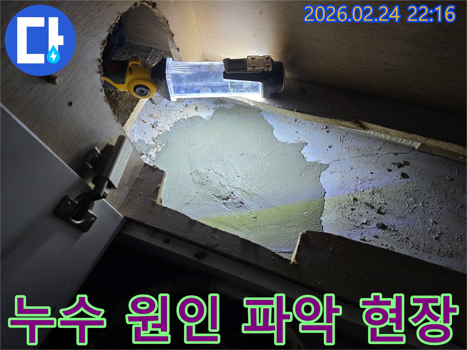 누수-전문가가-어두운-싱크대-하부에서-누수-원인을-파악하기-위해-조명-장비를-사용하여-정밀-조사하는-모습