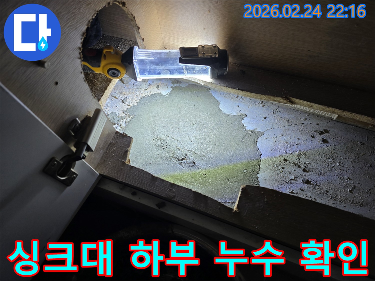 누수-전문가가-어두운-싱크대-하부에서-누수-지점을-확인하기-위해-조명-장비를-사용하여-꼼꼼히-탐지하는-모습