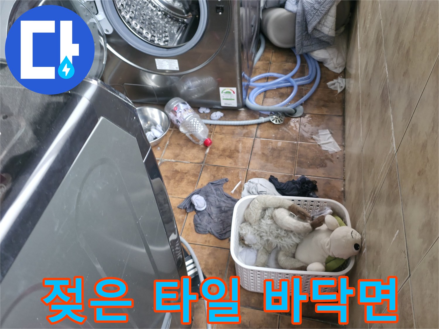 세탁기 주변의 젖어 있는 타일과 배수 호스 연결 부위입니다.