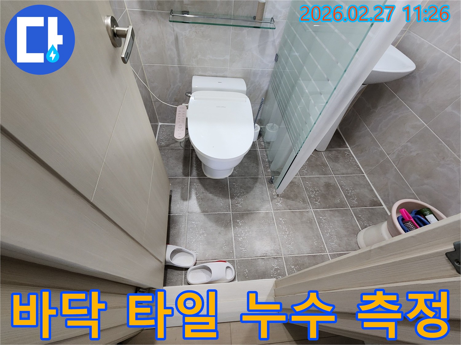 화장실 바닥 타일과-변기-비데-샤워부스가 보이는-공간에서-습기 측정 장비로-누수 지점을 찾는 모습