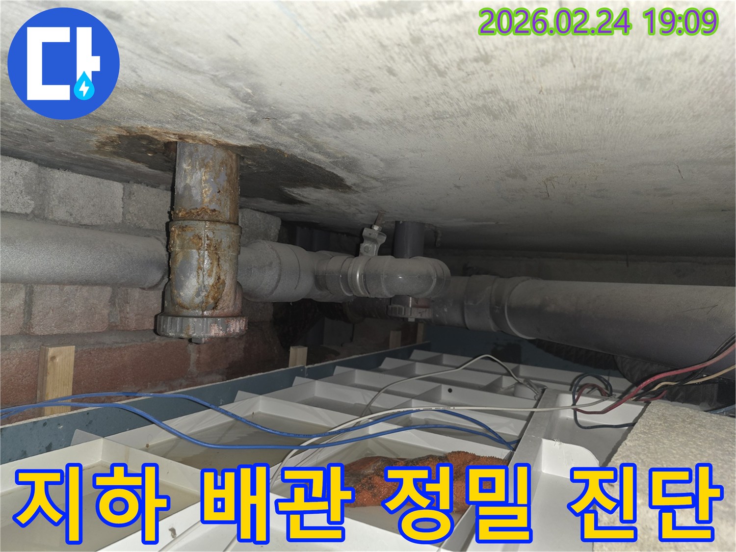 오래된 배관에서 물이 새어 나와 임시 물받이에 고인 물과 함께 보이는 현장