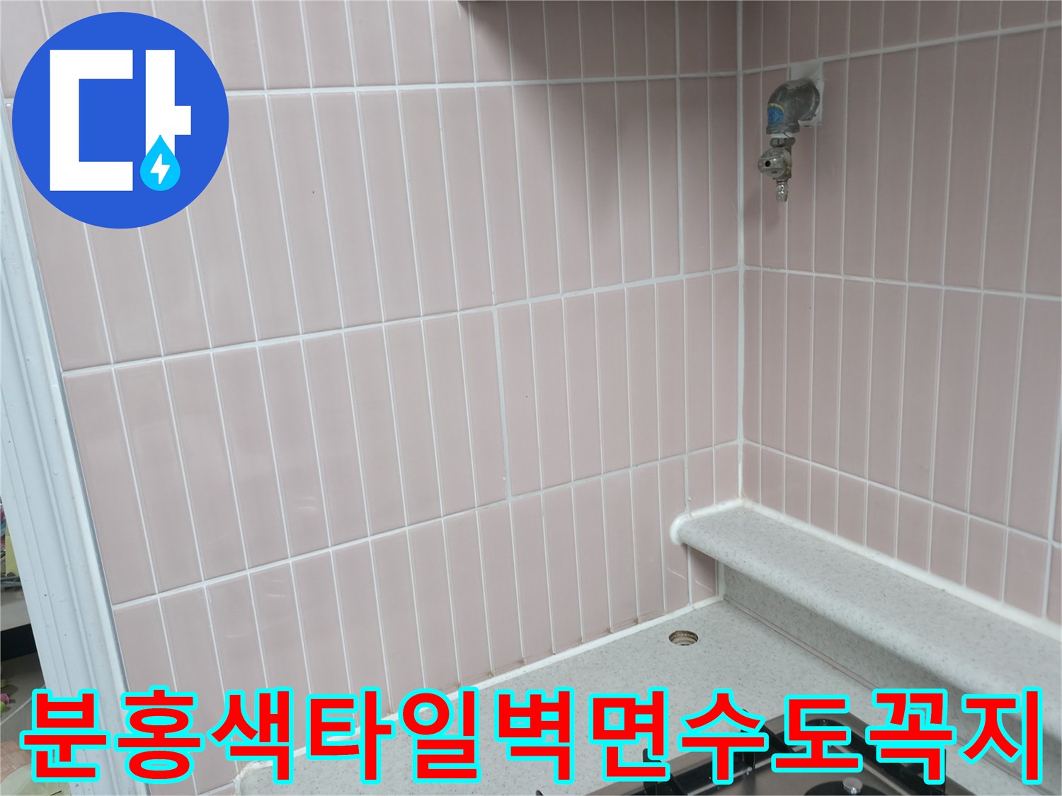 분홍색 세로형 타일 벽면과 금속 소재의 수도꼭지 모습