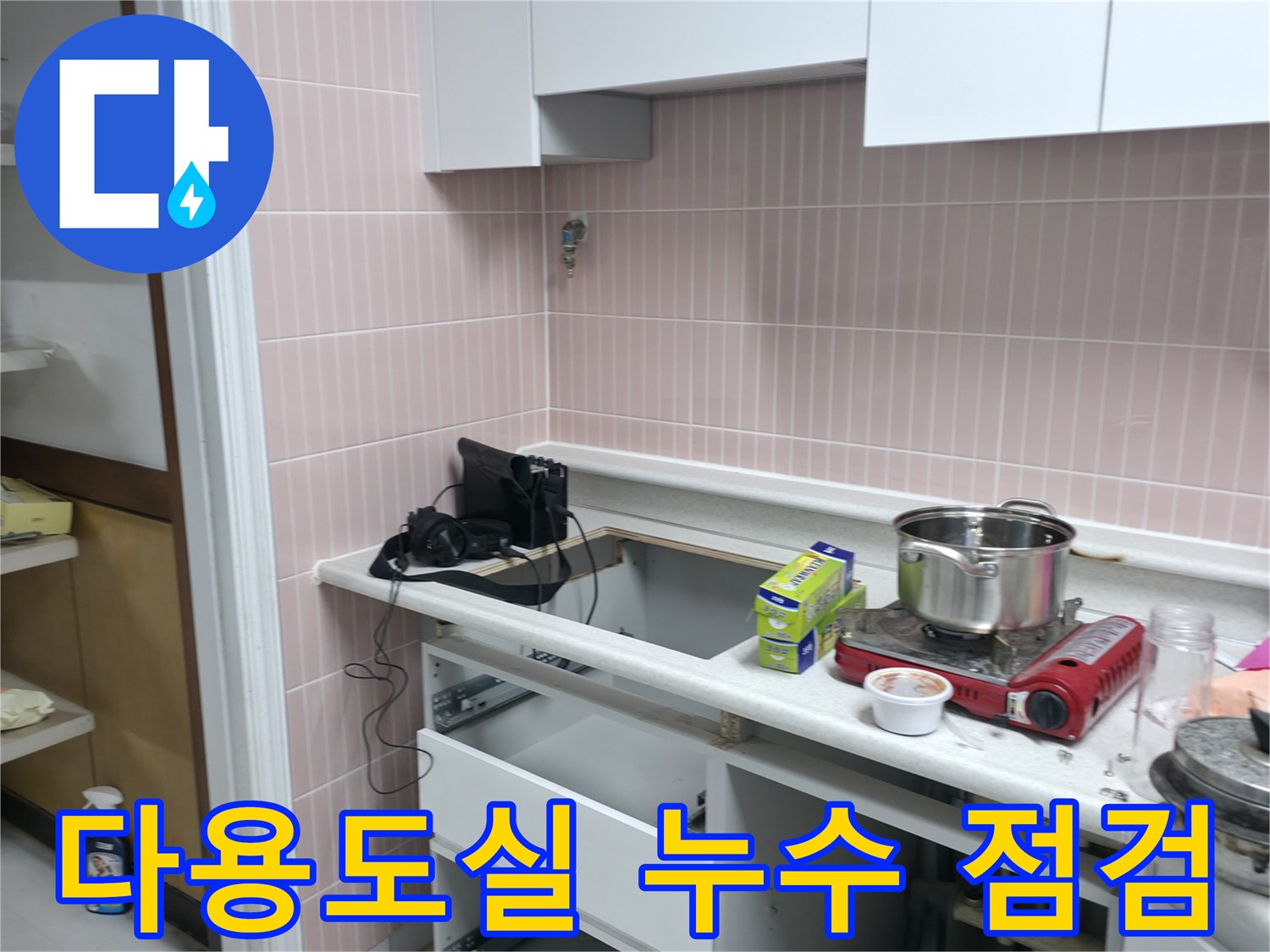 싱크대 아래쪽 공간에서-배수 호스의 파손 여부를 확인하고 있습니다.