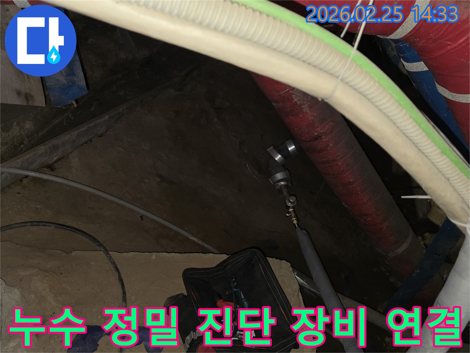 누수 원인을 정확히 파악하기 위해-전문 엔지니어가 정밀 진단 장비를-배관에 연결하는 중요한 작업 현장입니다.