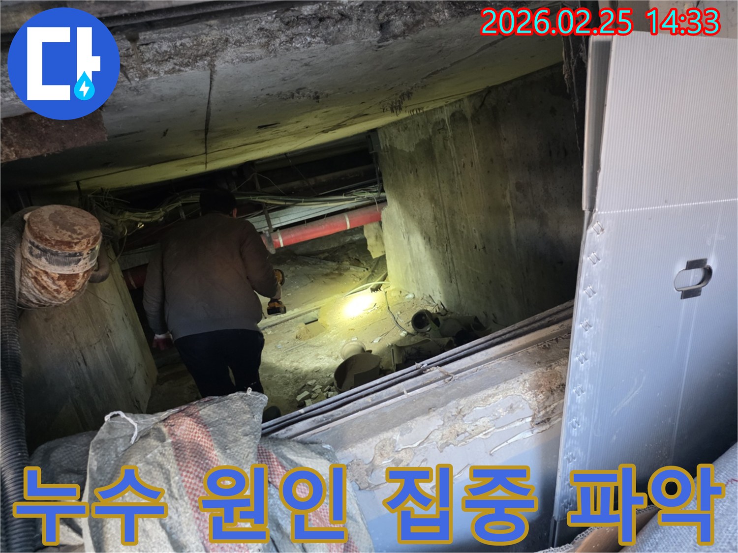누수 전문 엔지니어가-어둡고 좁은 공간에서-손전등을 비춰가며-배관의 누수 원인을-집중적으로 파악하는 모습입니다.
