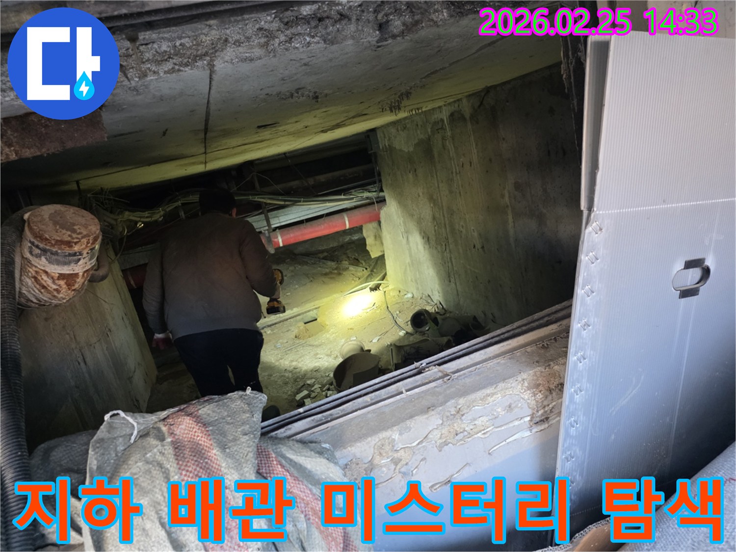 누수 전문 엔지니어가-어둡고 좁은 지하 공간에서-손전등을 비춰가며-배관의 숨겨진 누수 지점을-정밀하게 탐색하여-미스터리를 해결하는 모습입니다.