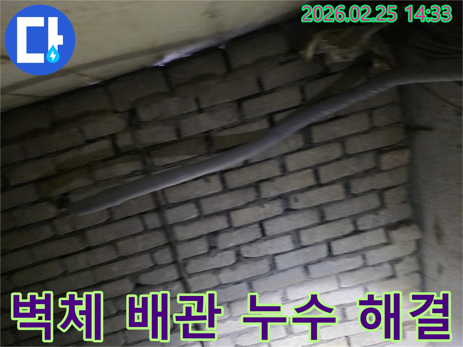 어두운 벽돌 벽면을 배경으로-단열된 배관과 함께-누수 여부를 확인하기 위해-정밀하게 검사되는 현장 모습입니다.