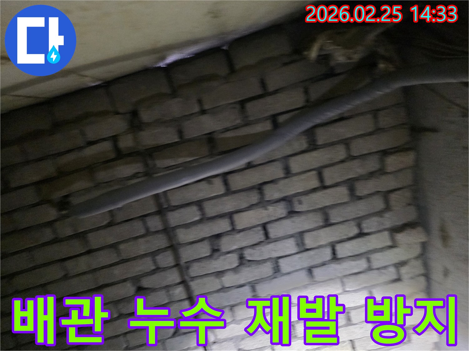 어두운 벽돌 벽면을 배경으로-단열된 배관과 함께-누수 재발 방지를 위해-정밀하게 검사되는 현장 모습입니다.