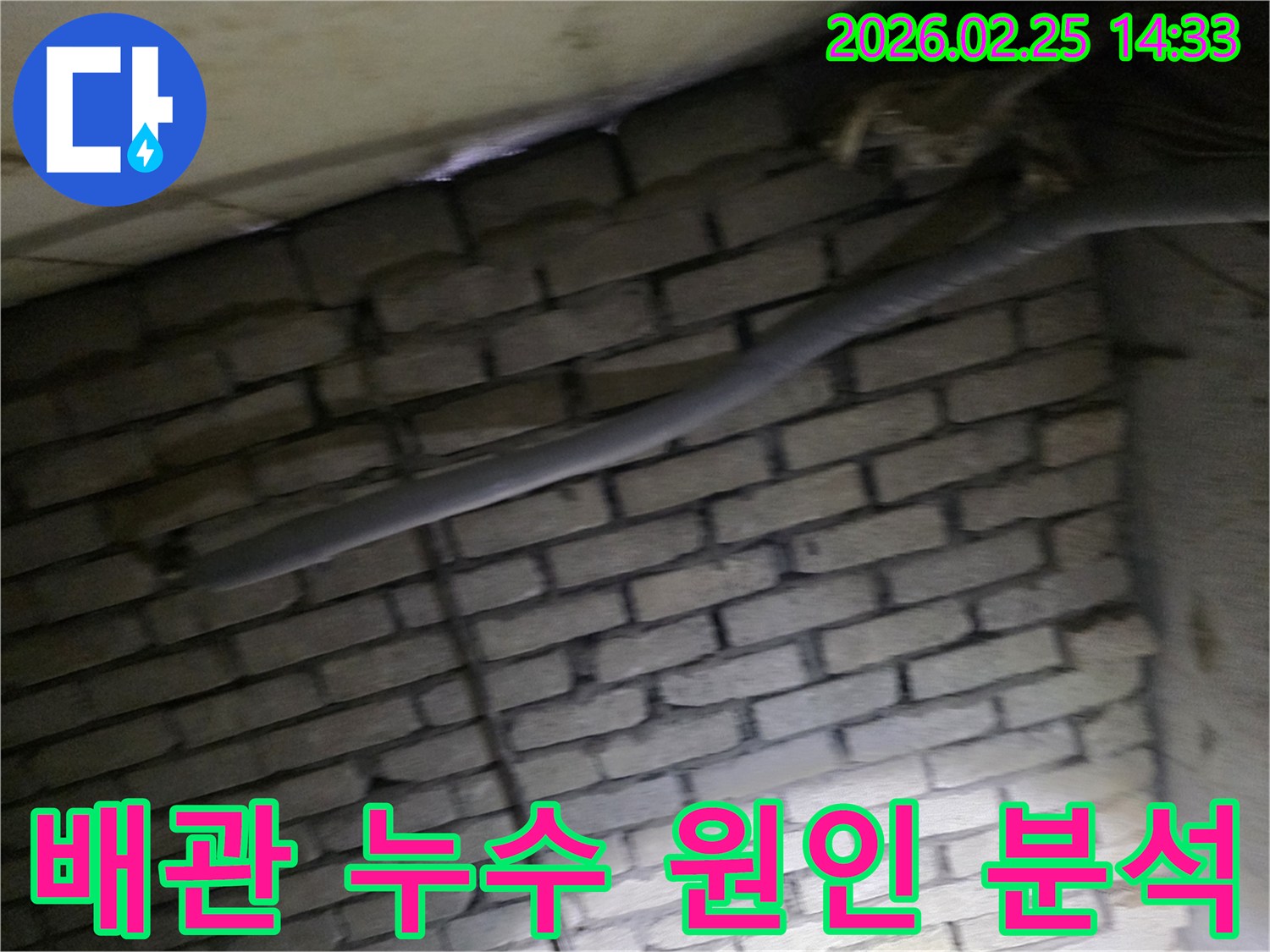 어두운 벽돌 벽면을 배경으로-단열재로 감싸인 배관에서-누수 원인을 정밀하게-분석하기 위해 촬영된 현장 이미지입니다.