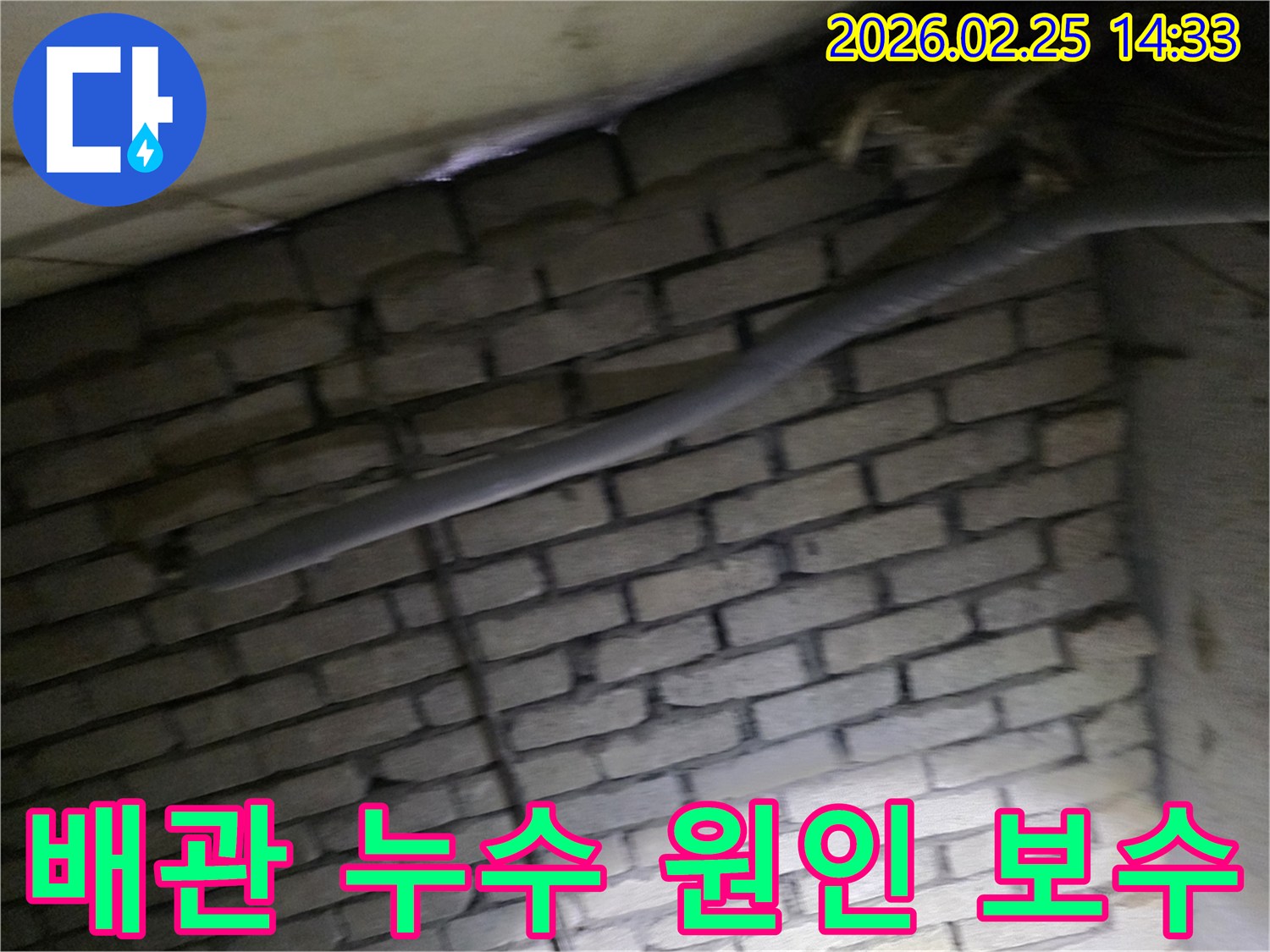 어두운 벽돌 벽면을 배경으로-단열재로 감싸인 배관에서-누수 원인을 파악하고-보수 작업을 준비하는 현장 이미지입니다.
