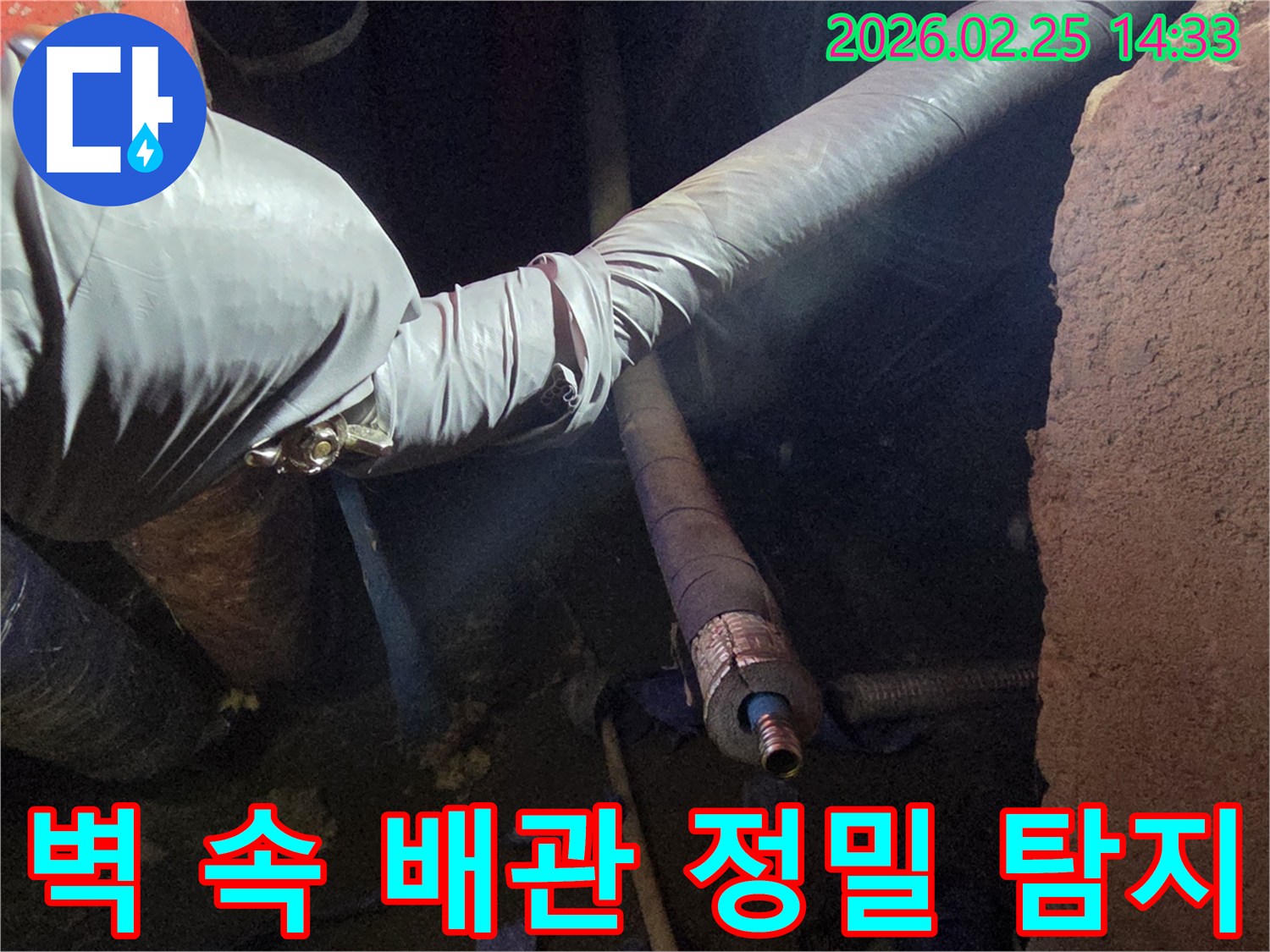 어두운 벽체 내부에서-장갑을 낀 손이-손상된 배관의-연결 부위를-세심하게 점검하며-누수 원인을-확인하는 모습입니다