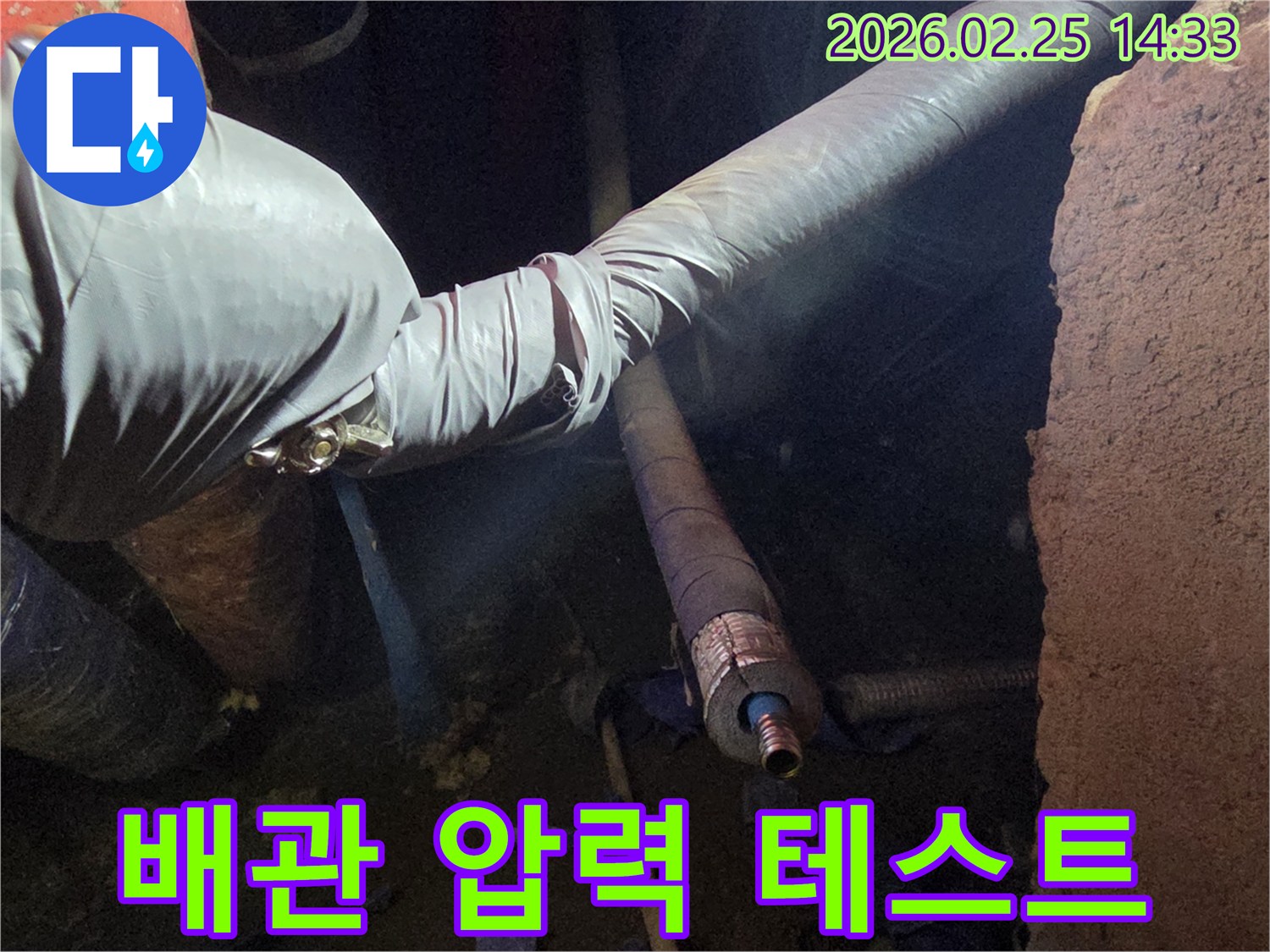 어두운 작업 공간에서-장갑을 낀 손이-배관에 압력을 가하여-누수 여부를-정확하게 확인하는-테스트 과정을-진행하는 모습입니다