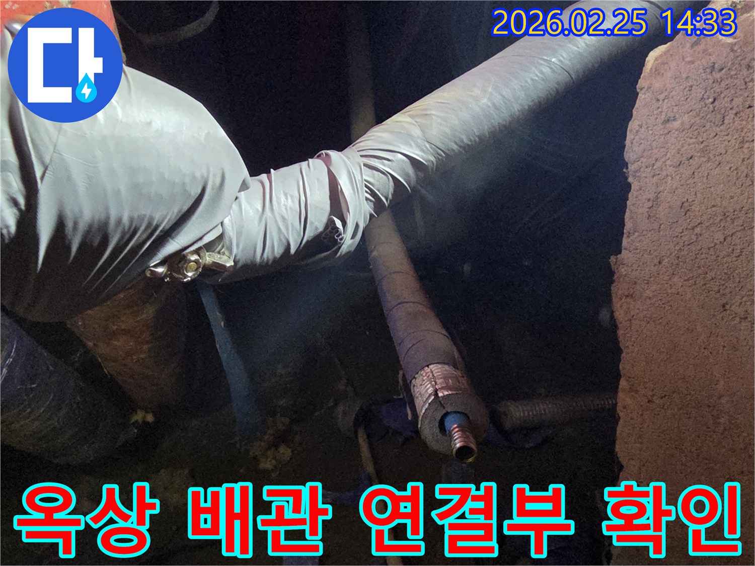 어두운 작업 공간에서-장갑을 낀 손이-옥상 배관의-연결 부위를-세심하게 점검하며-누수 원인을-확인하는 모습입니다