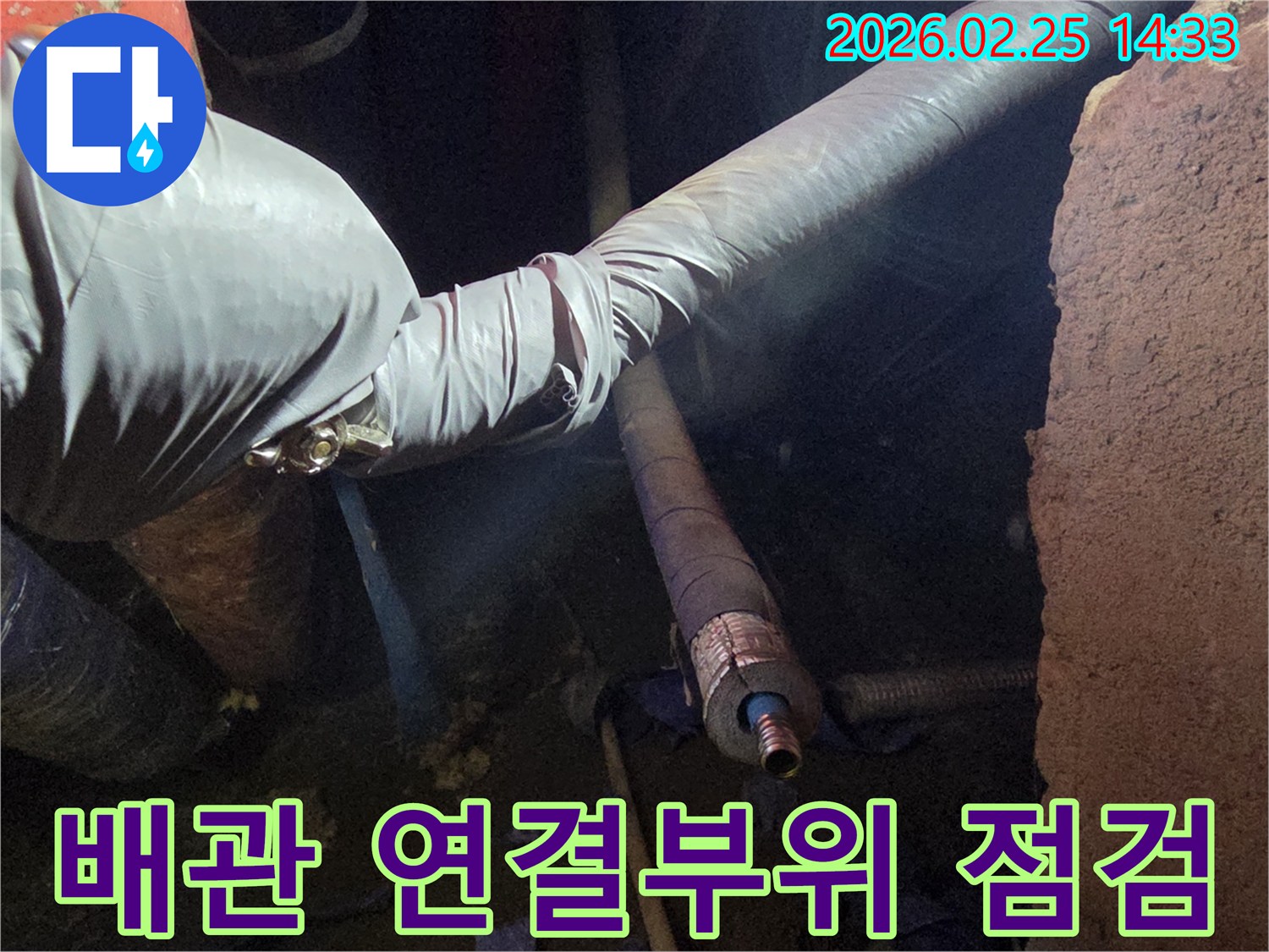 어두운 작업 공간에서-전문 기술자가-장갑을 끼고-배관의 연결 부위를-세심하게 확인하며-누수 여부를-점검하는 모습입니다