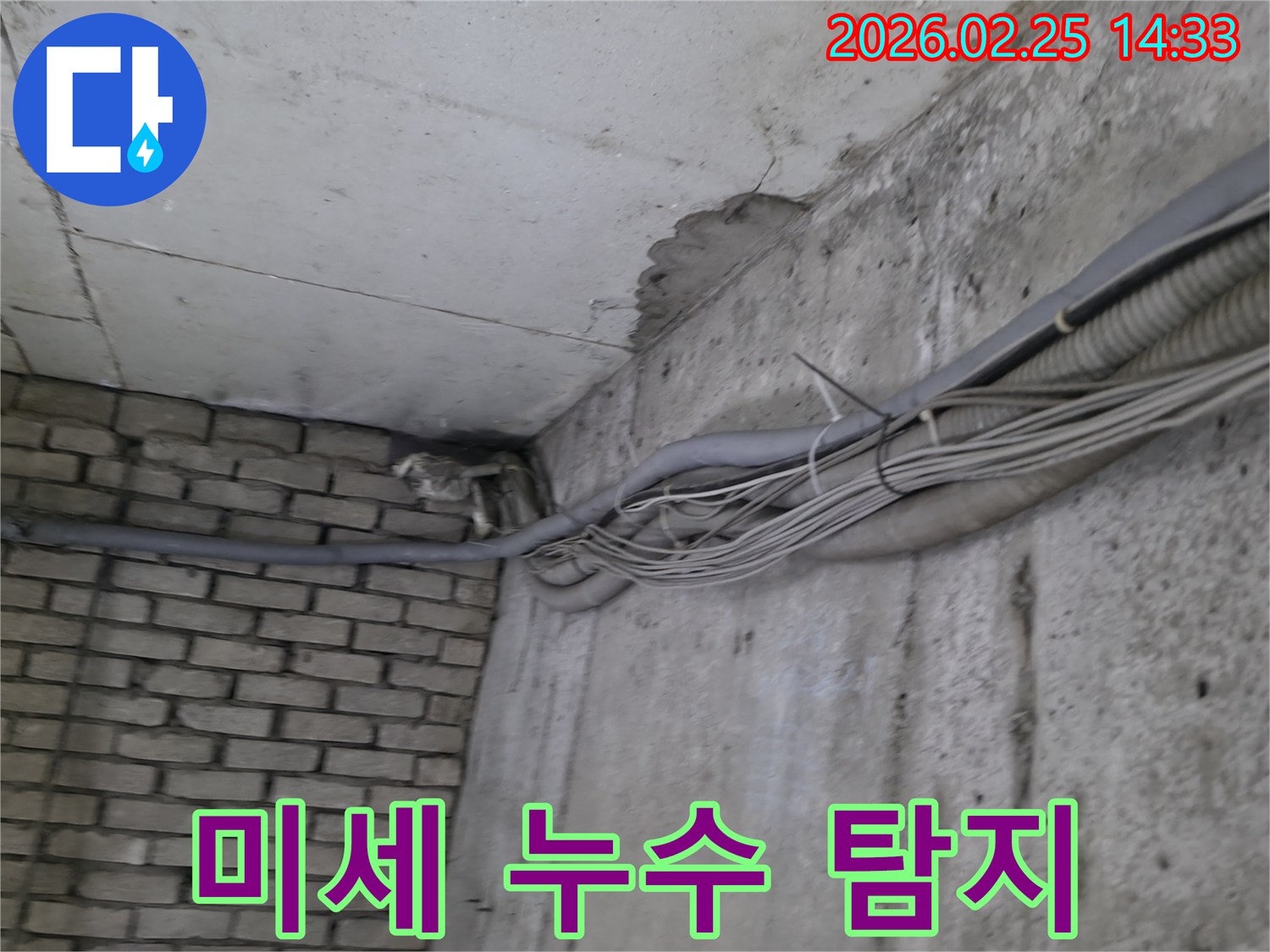 지하 벽면의-콘크리트와-벽돌 벽이 만나는-지점에서-발견된-오랜 누수로 인한-물자국과-주변의 복잡한 배관
