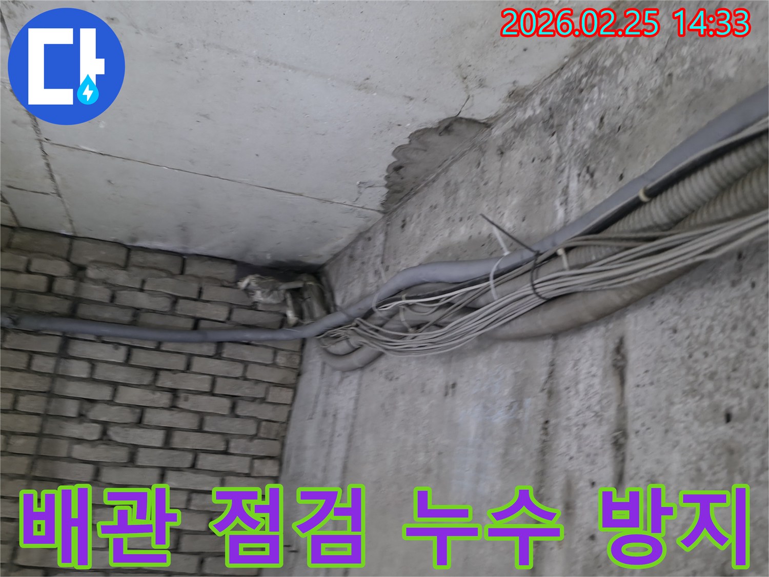 지하 벽면의-콘크리트와-벽돌 벽이 만나는-지점에서-발견된-오랜 누수로 인한-물자국과-주변의 복잡한 배관