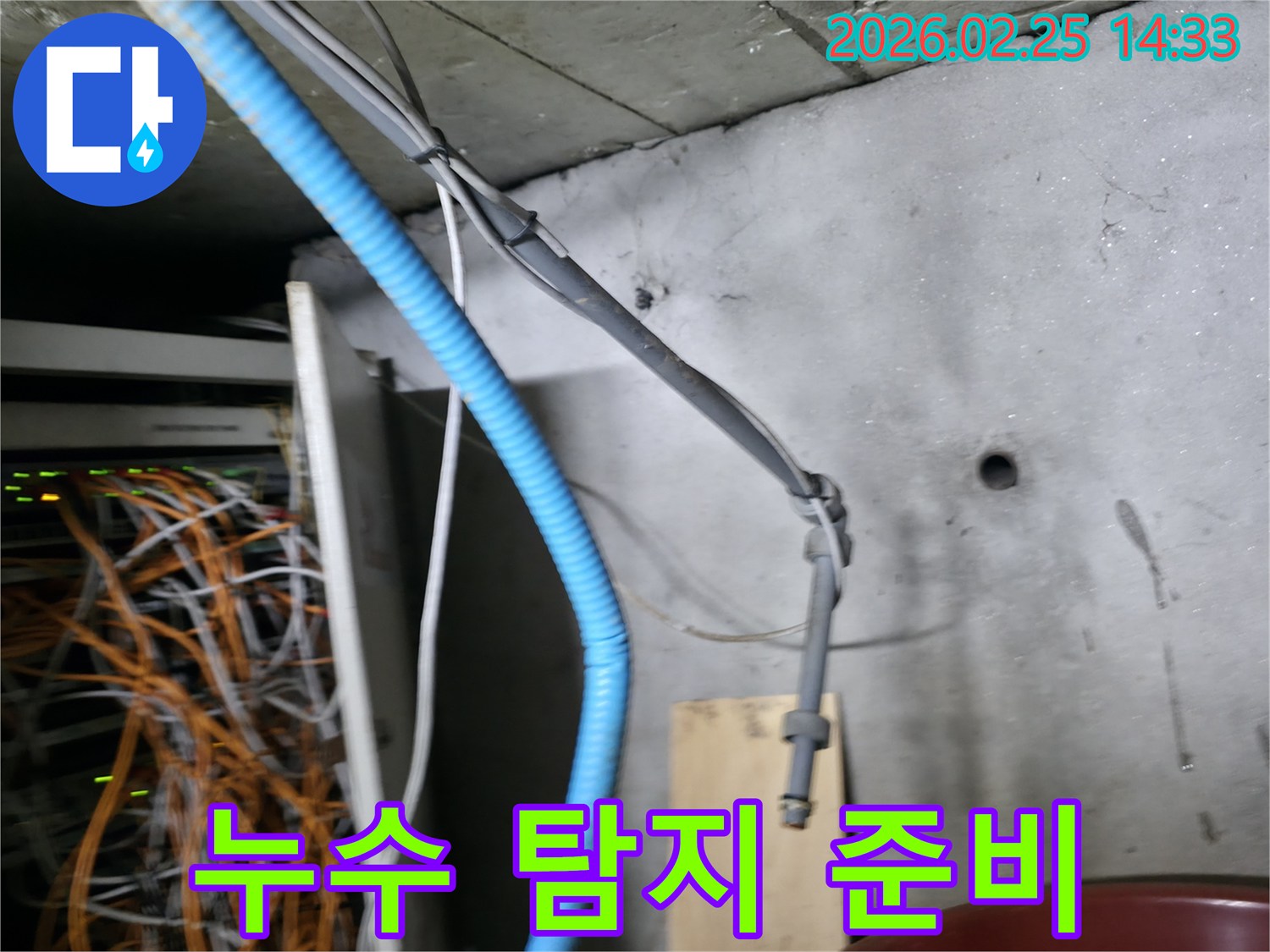 콘크리트 벽면에 고정된-파란색 주름관과 회색 케이블들이-누수 탐지 작업의-중요한 단서가 될 수 있음을-시각적으로 보여줍니다
