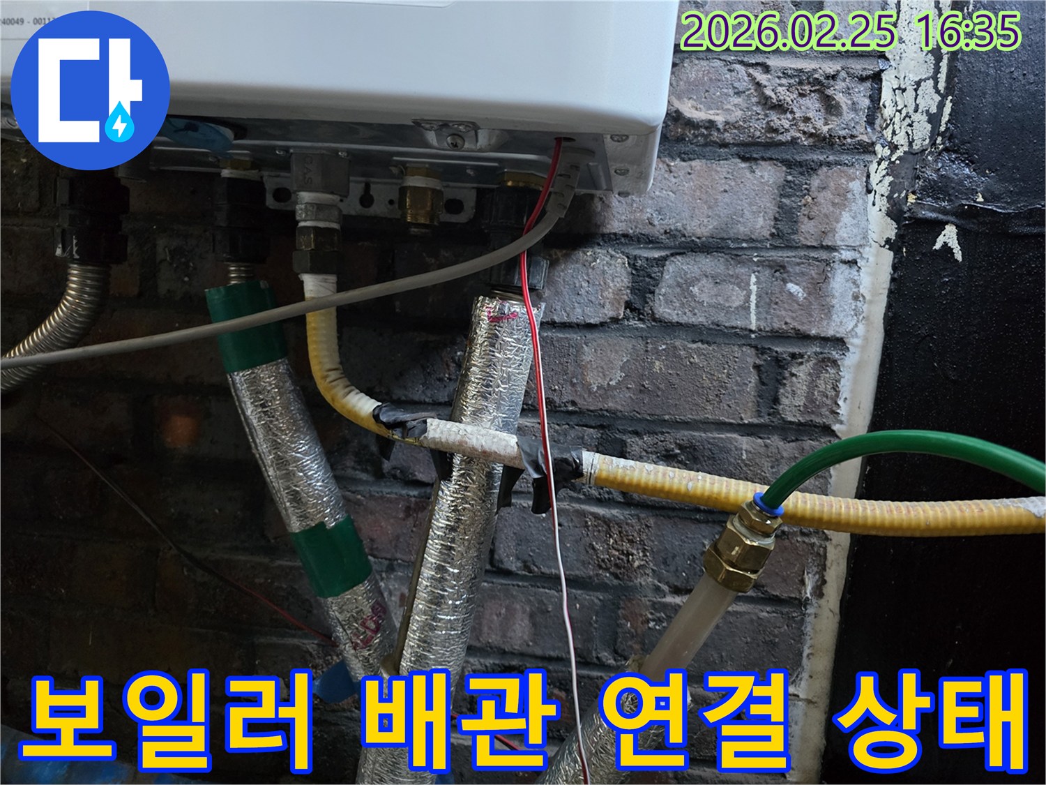 이 이미지는-벽에 설치된-보일러 하단부의-다양한 배관 연결부와-전선-그리고-은색 단열재로-감싸진-파이프들을-보여주며-정밀한 점검이-필요한-상황을-나타냅니다.