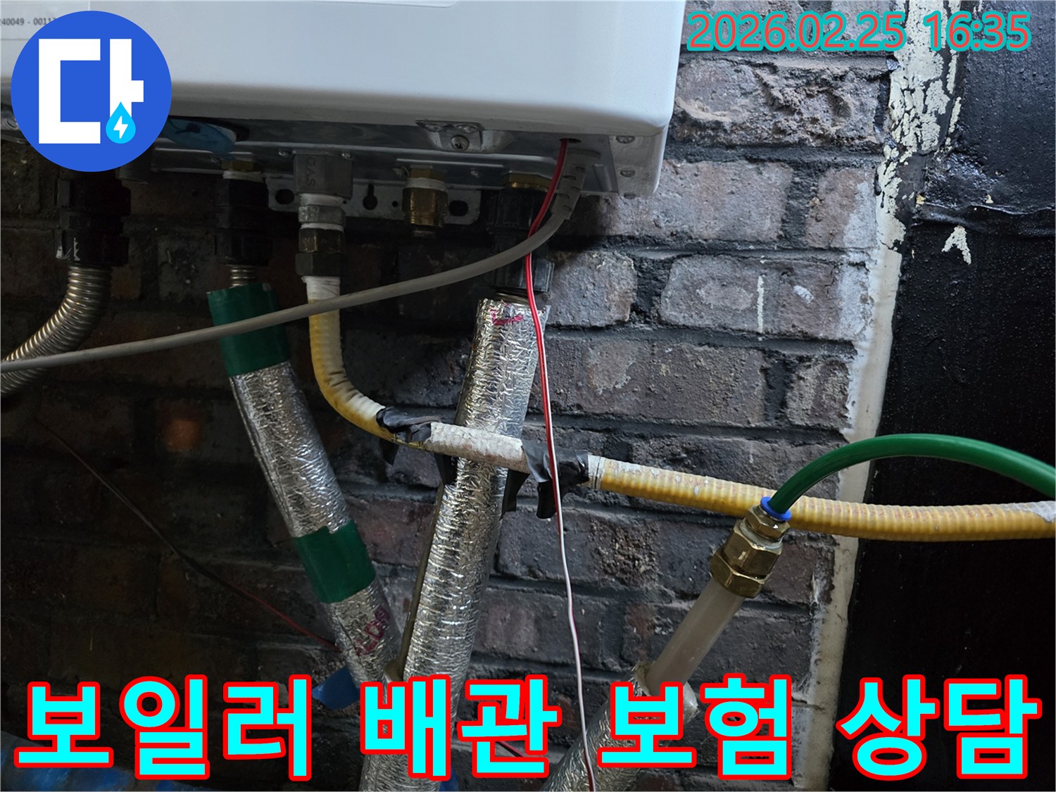 이 이미지는-벽에 설치된-보일러 하단부의-복잡한 배관 연결부와-전선-그리고-은색 단열재로-감싸진-파이프들을-보여주며-누수 보험 처리를-위한-점검이-진행되고-있음을-암시합니다.