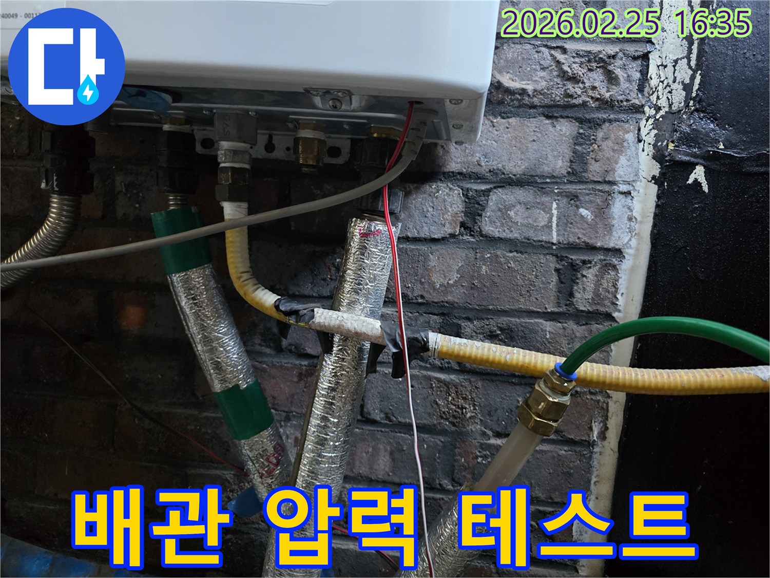이 이미지는-보일러 하부의-배관들이-연결된-모습을-보여주며-누수 지점을-찾기 위한-압력 테스트-준비 또는-진행 상황을-나타냅니다.