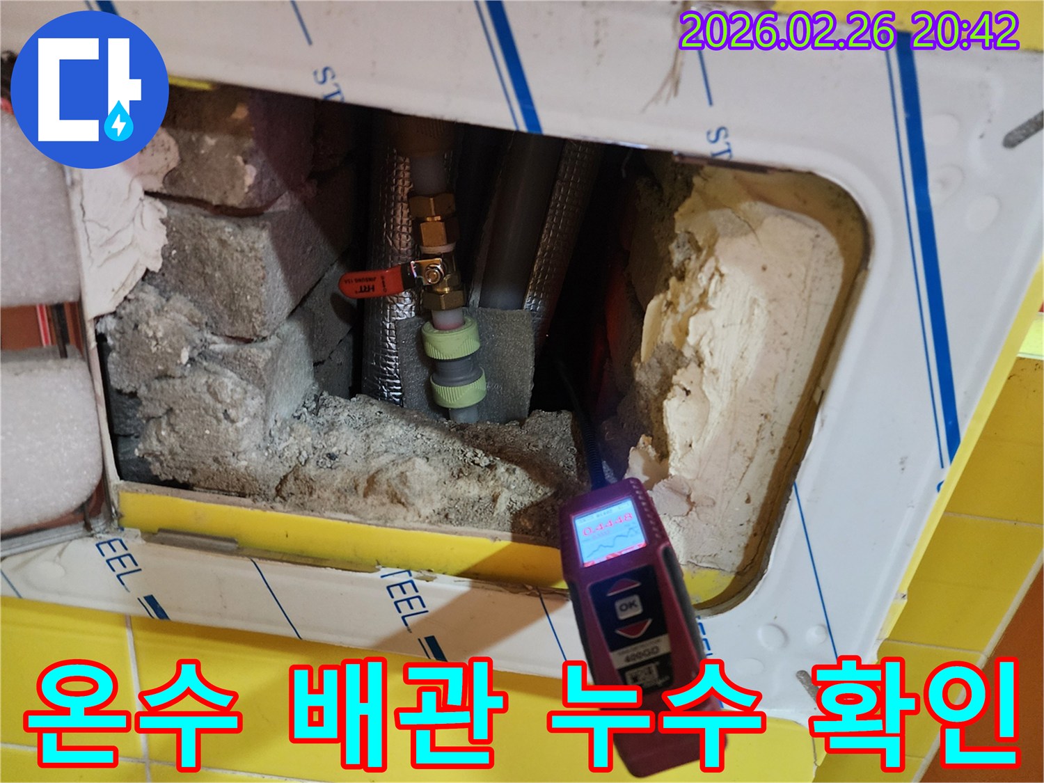 누수 탐지 엔지니어가-특수 장비로-온수 배관 주변의-습기를 측정하며-누수 지점을 찾는 장면