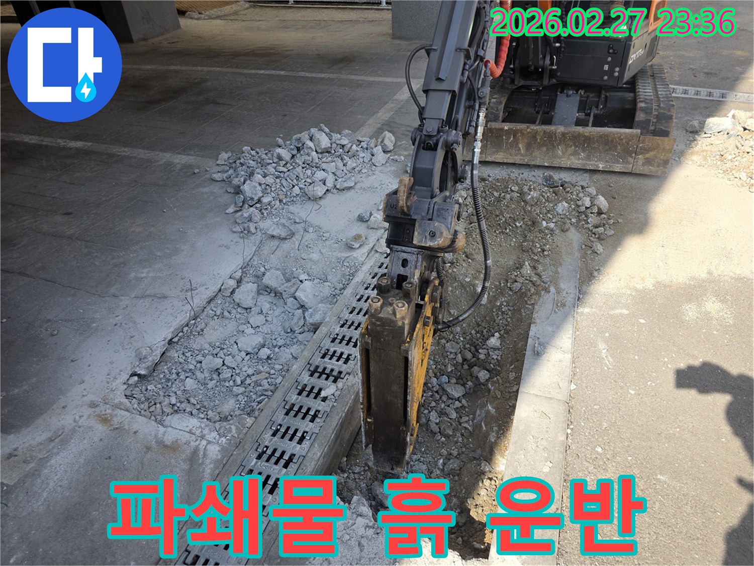 누수-공사-현장에서-파쇄된-콘크리트와-흙을-굴삭기-버킷으로-담아-처리하는-작업-모습
