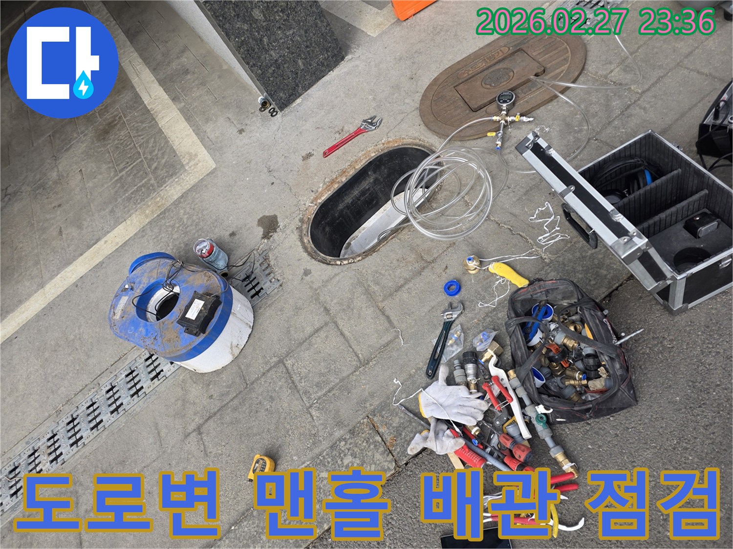 도로변에-위치한-맨홀을-개방하여-지하-배관에-접근하고-누수-여부를-점검하는-모습
