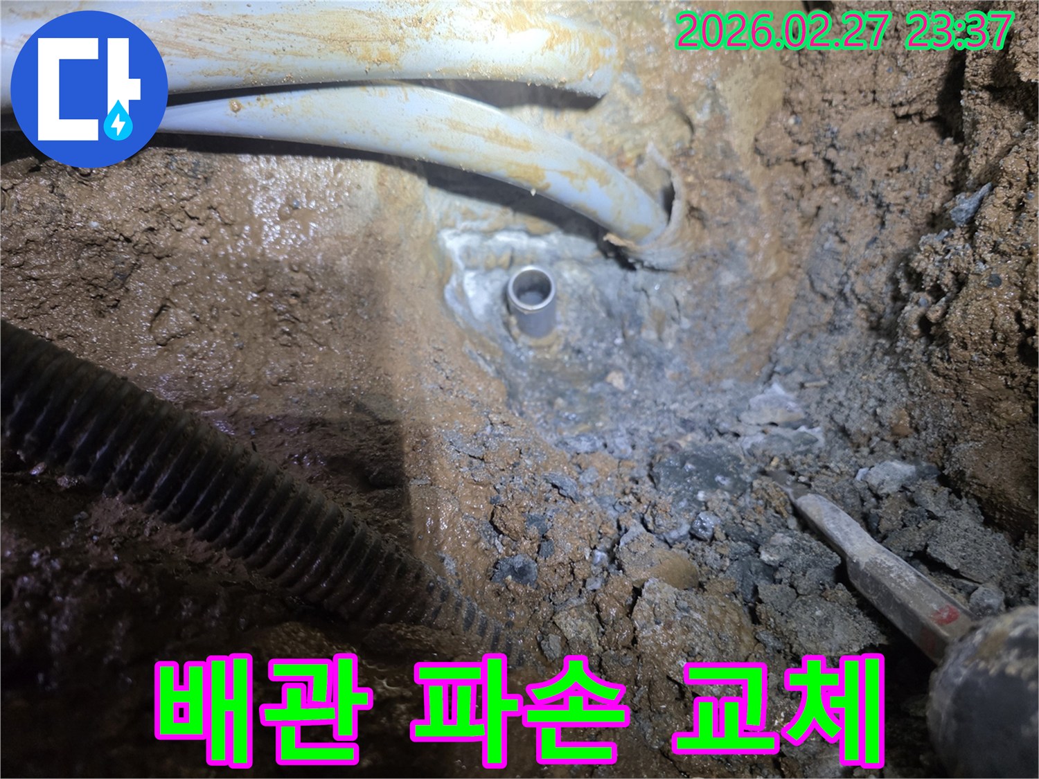 흙 속에서 드러난-파손된 배관을 새로운 배관으로 교체하는 작업 현장