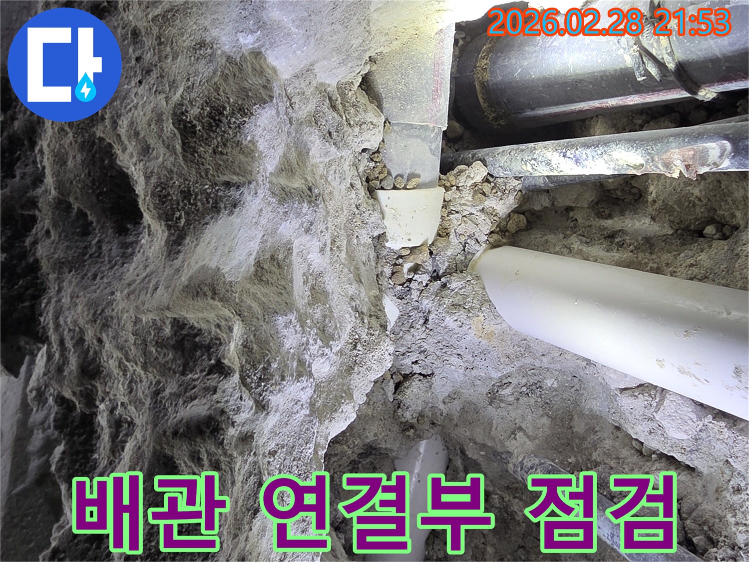 어두운 공간에서-흙과 자갈 속에 묻힌-다양한 배관들의-복잡한 연결부를-점검하는 누수 전문가의 모습