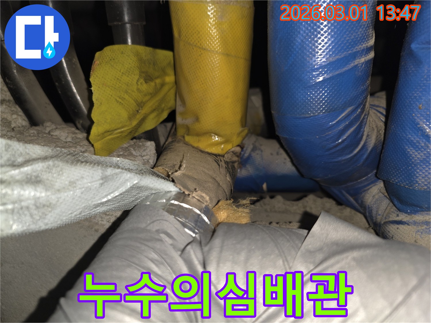 노후화된 배관의 보온재가 파손되어-에너지 손실과 누수 위험이 있는 장면입니다.