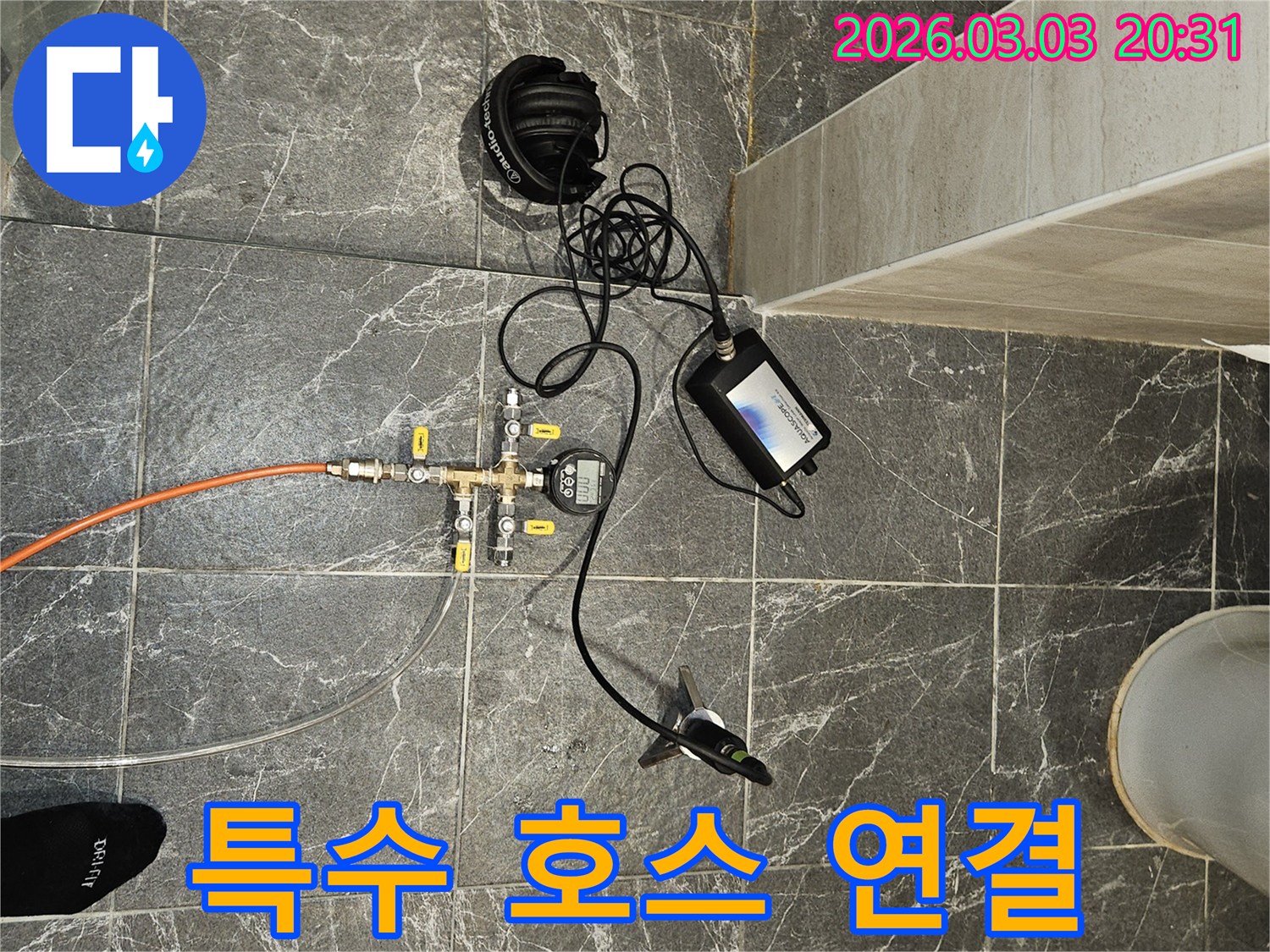 수도관 누수 지점을 찾기 위해-특수 호스를 배관에 연결하여-정밀 검사를 준비하는 현장입니다.