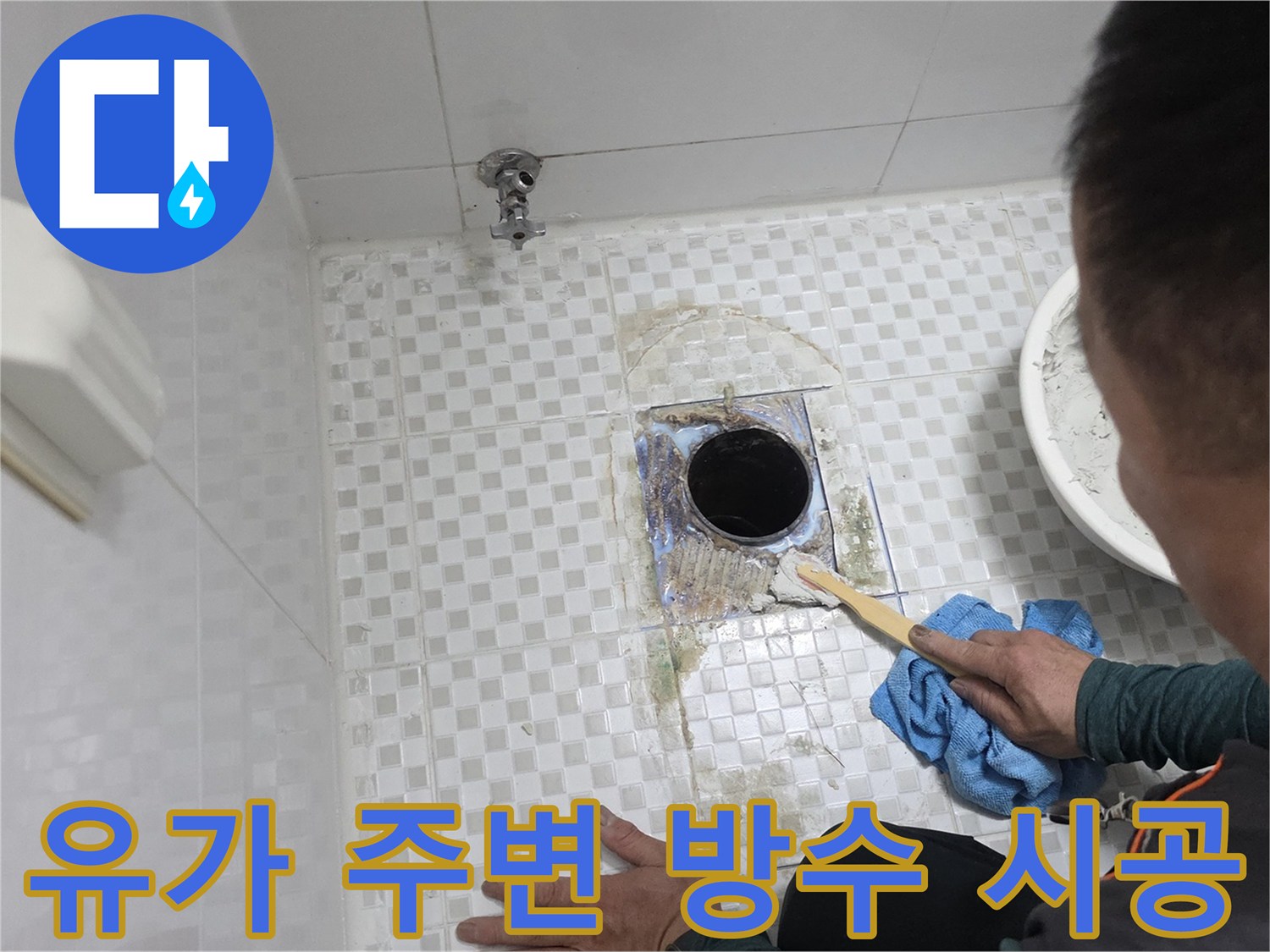 엔지니어가 붓을 활용하여 배수구 근처 타일 틈에 방수제를 채우고 있습니다.